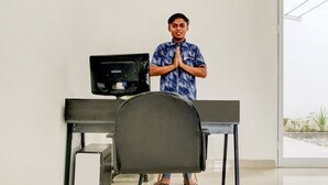 A person standing in front of a Samsung monitor on a desk with a chair in front of it, in a room with a large window. - Hotel O Panakkukang Near Mall Panakkukang Formerly Golden White House (Makassar)