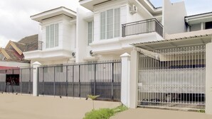 A modern two-story house with a gated entrance, a balcony, and a covered porch. - Hotel O Panakkukang Near Mall Panakkukang Formerly Golden White House (Makassar)