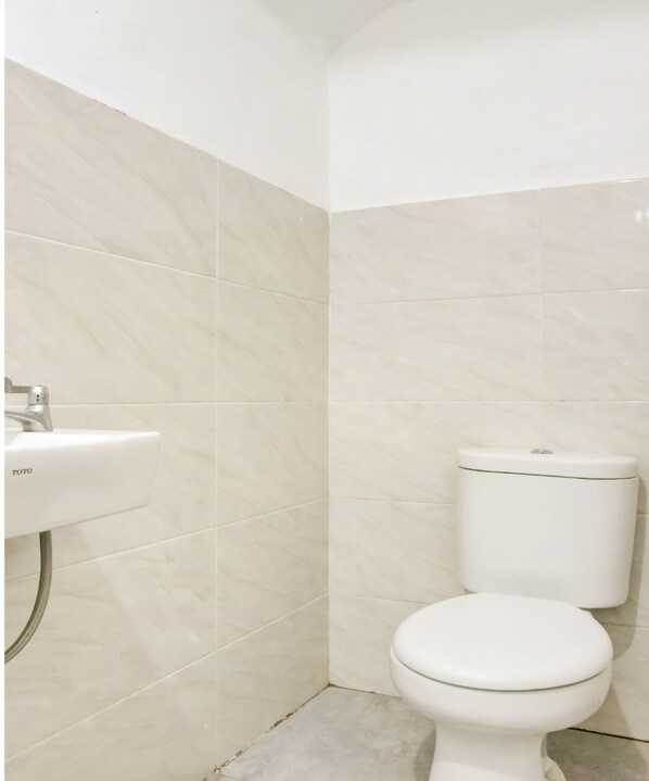 A bathroom with a white toilet and a TOTO sink. - Hotel O Panakkukang Near Mall Panakkukang Formerly Golden White House (Makassar)
