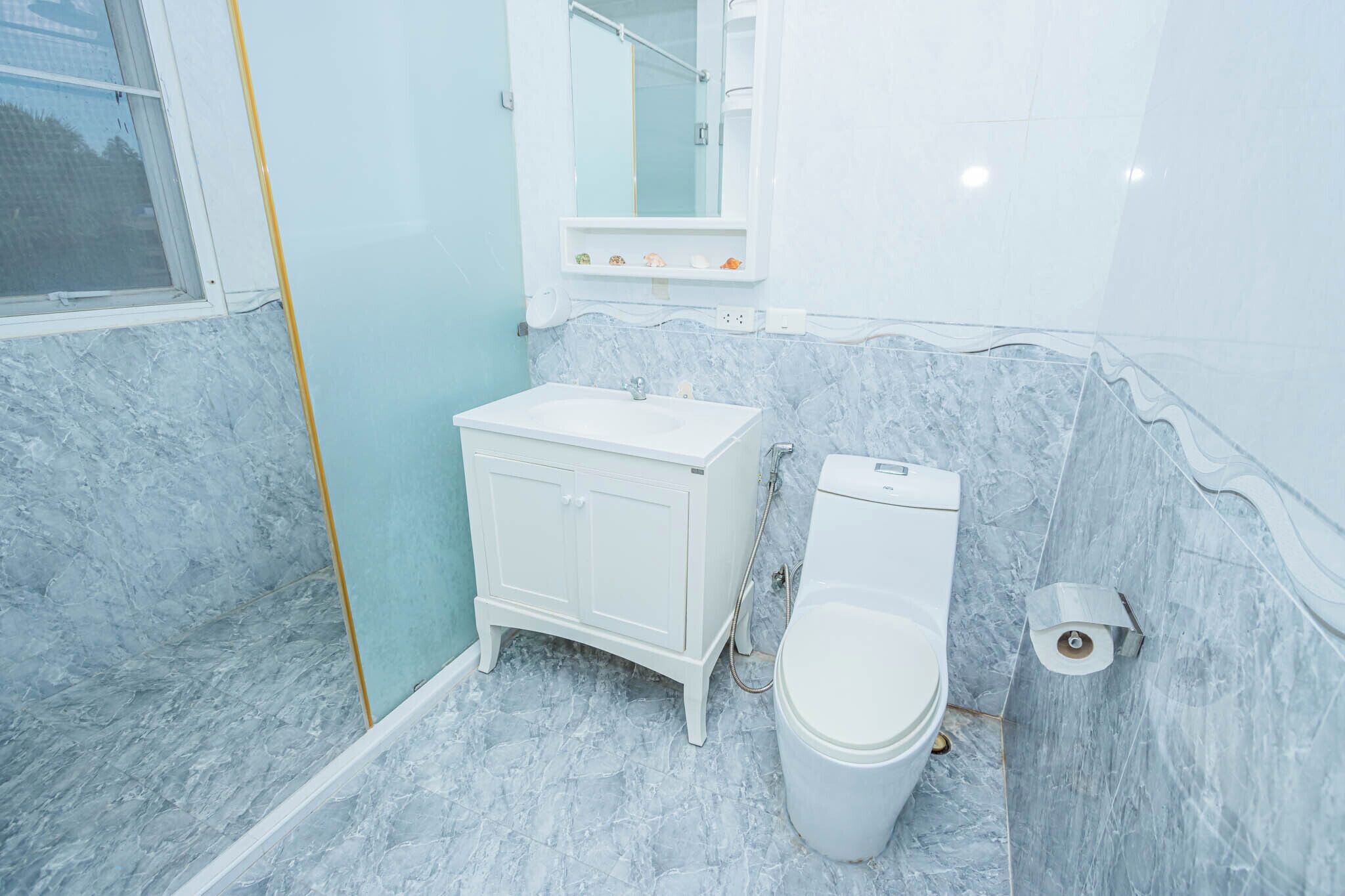 A bathroom with a white vanity, a toilet, and a marble floor.