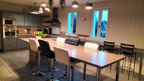 Une cuisine moderne dotée d’un îlot central, de tabourets de bar et d’une table à manger.