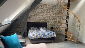 Une chambre à coucher avec un lit, un escalier en bois, un mur en pierre et un design moderne.