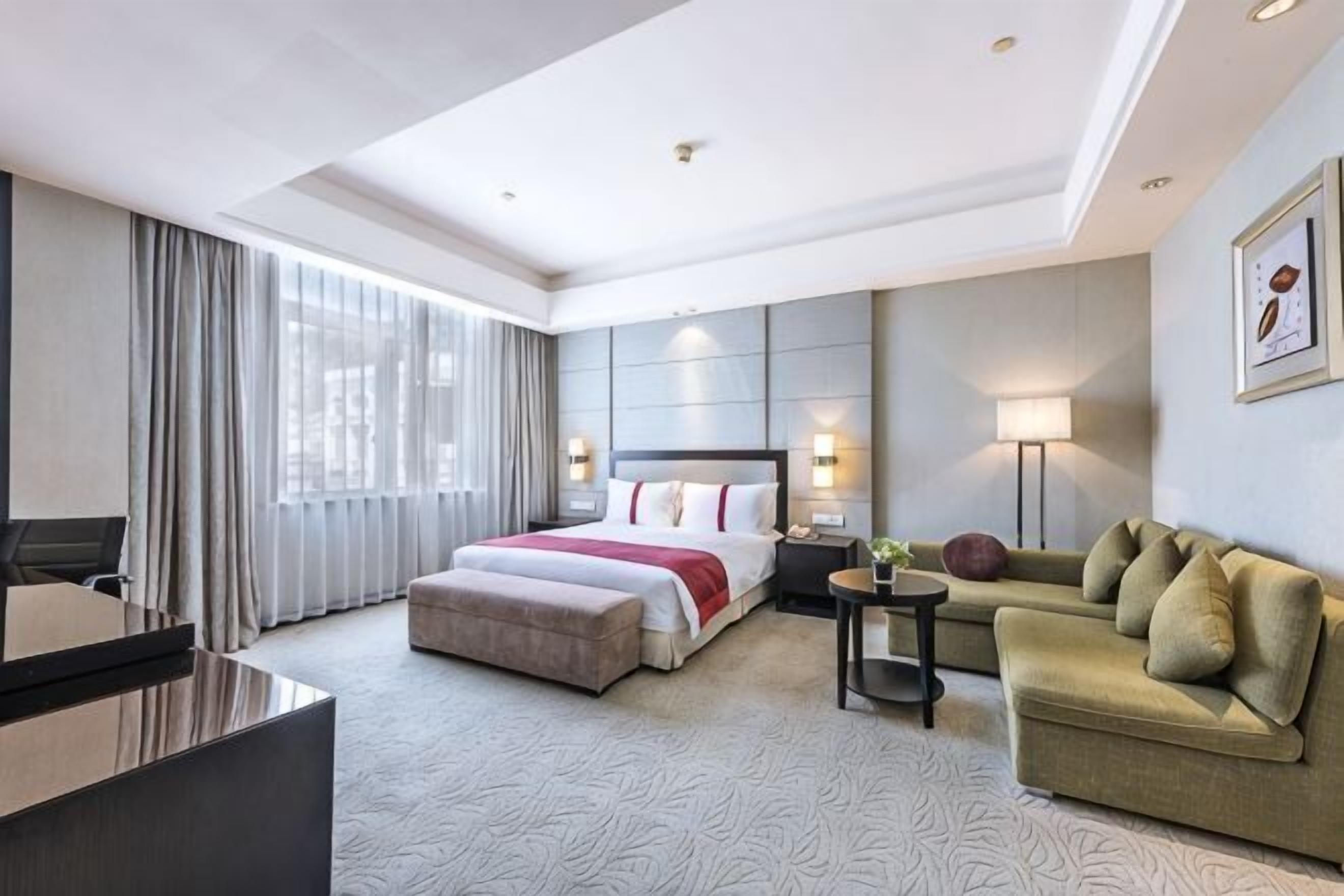 Et hotelværelse med seng, sofa, skrivebord og lampe.