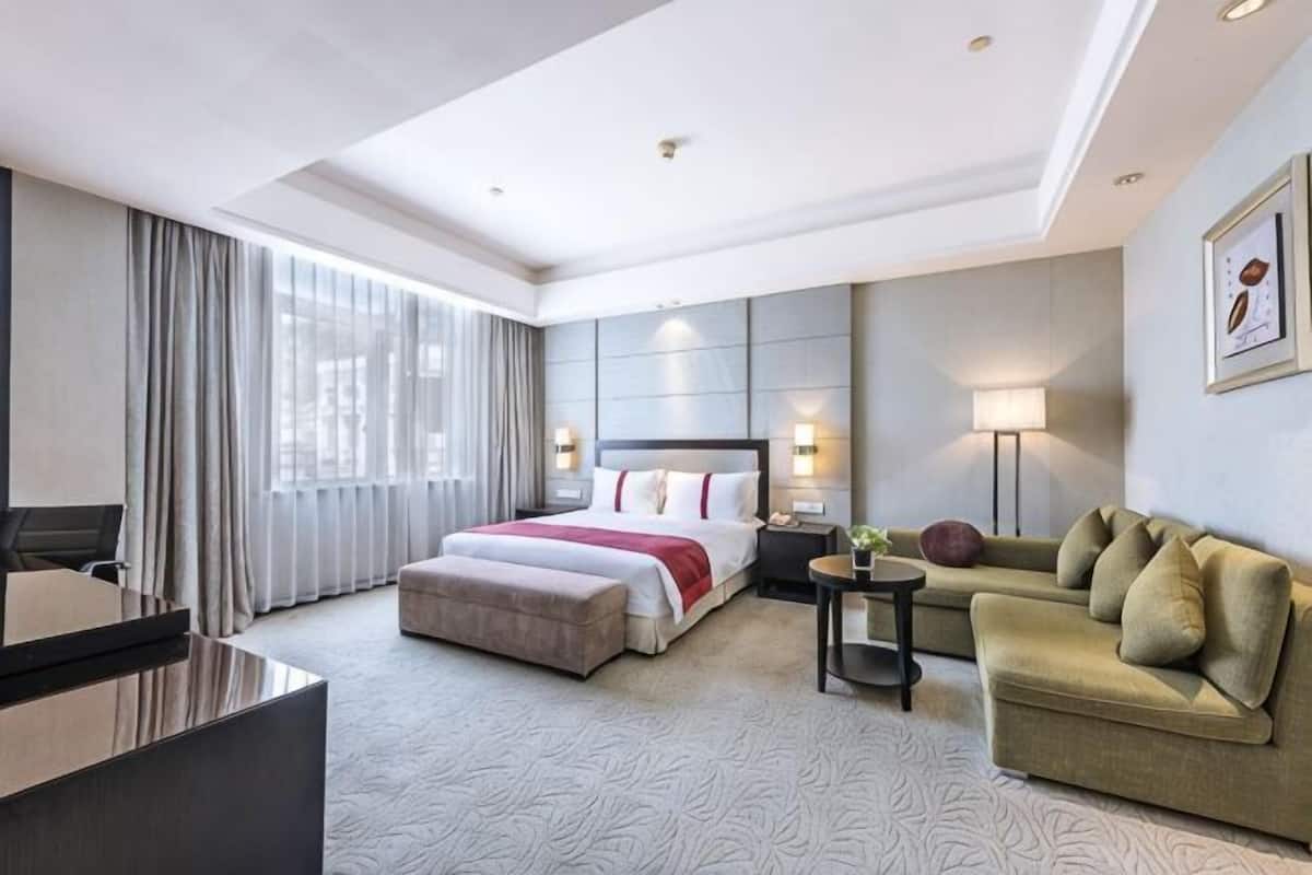 Une chambre d’hôtel avec un lit, un canapé, un bureau et une lampe.