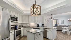 A modern kitchen with white cabinetry, stainless steel appliances, and a central island. - Summer House Beachfront Condos (Orange Beach)