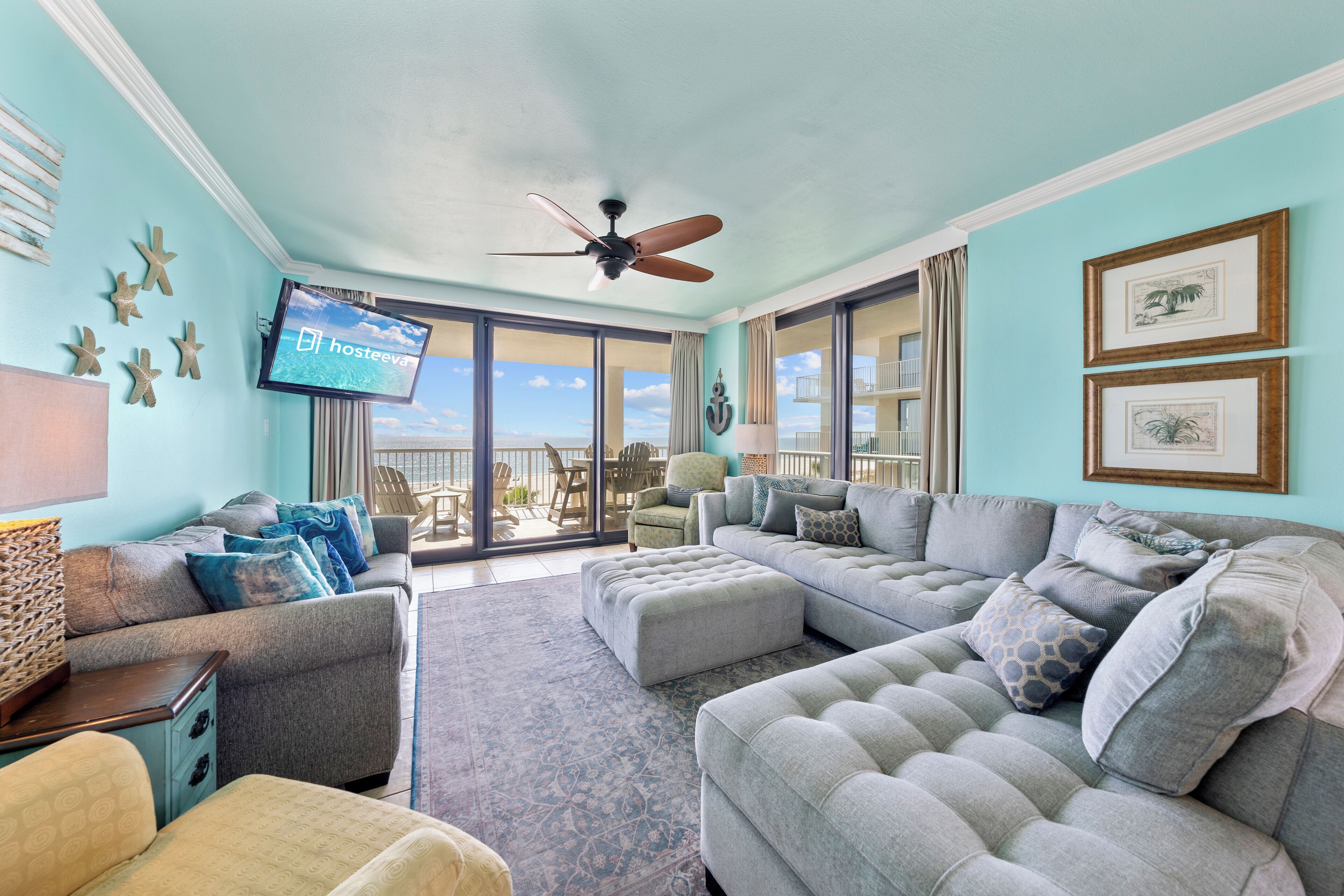 A spacious living room with a large sectional sofa, a television, and a balcony with a view.