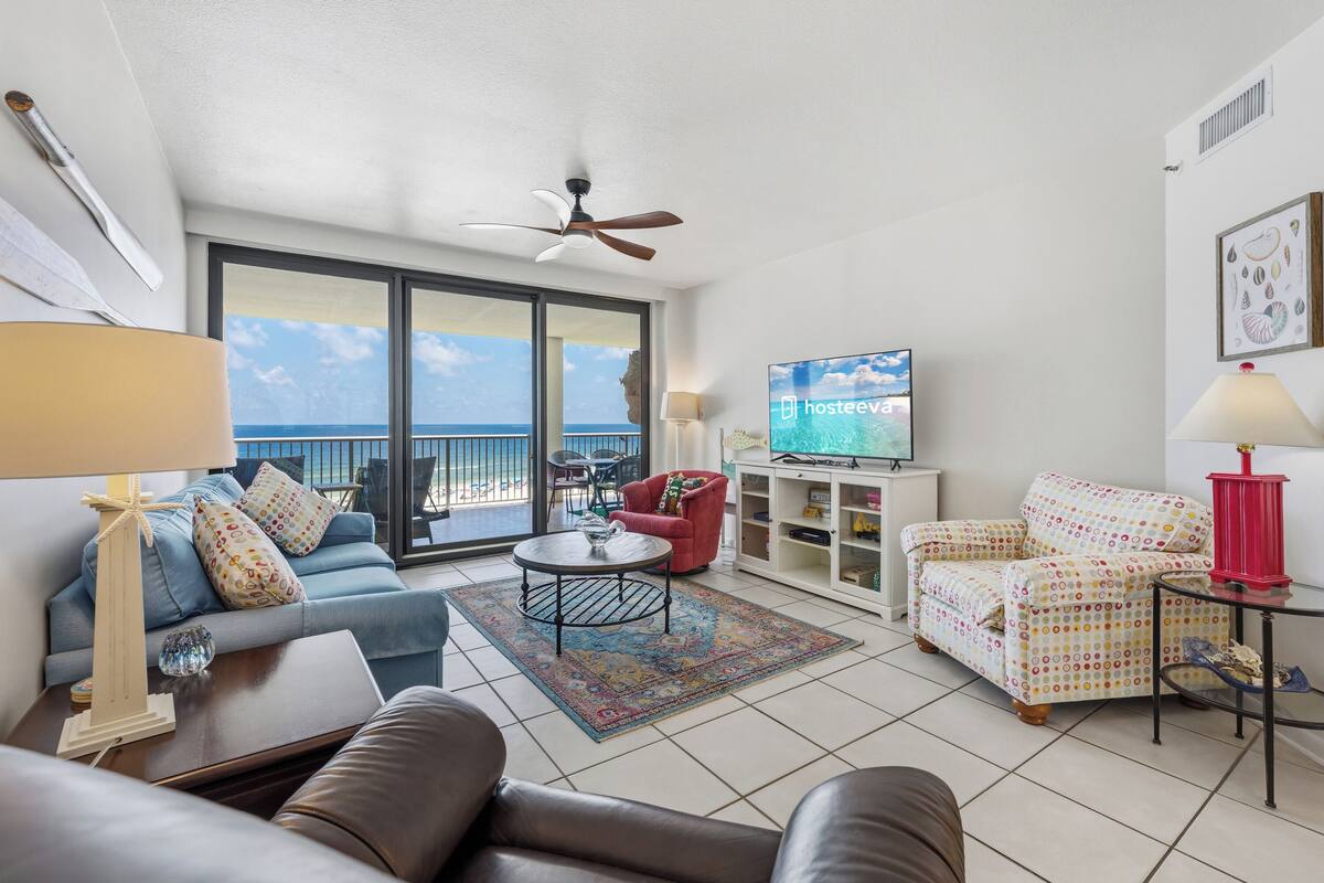 Una sala de estar con sofá, sillón, televisor y un balcón con vistas.