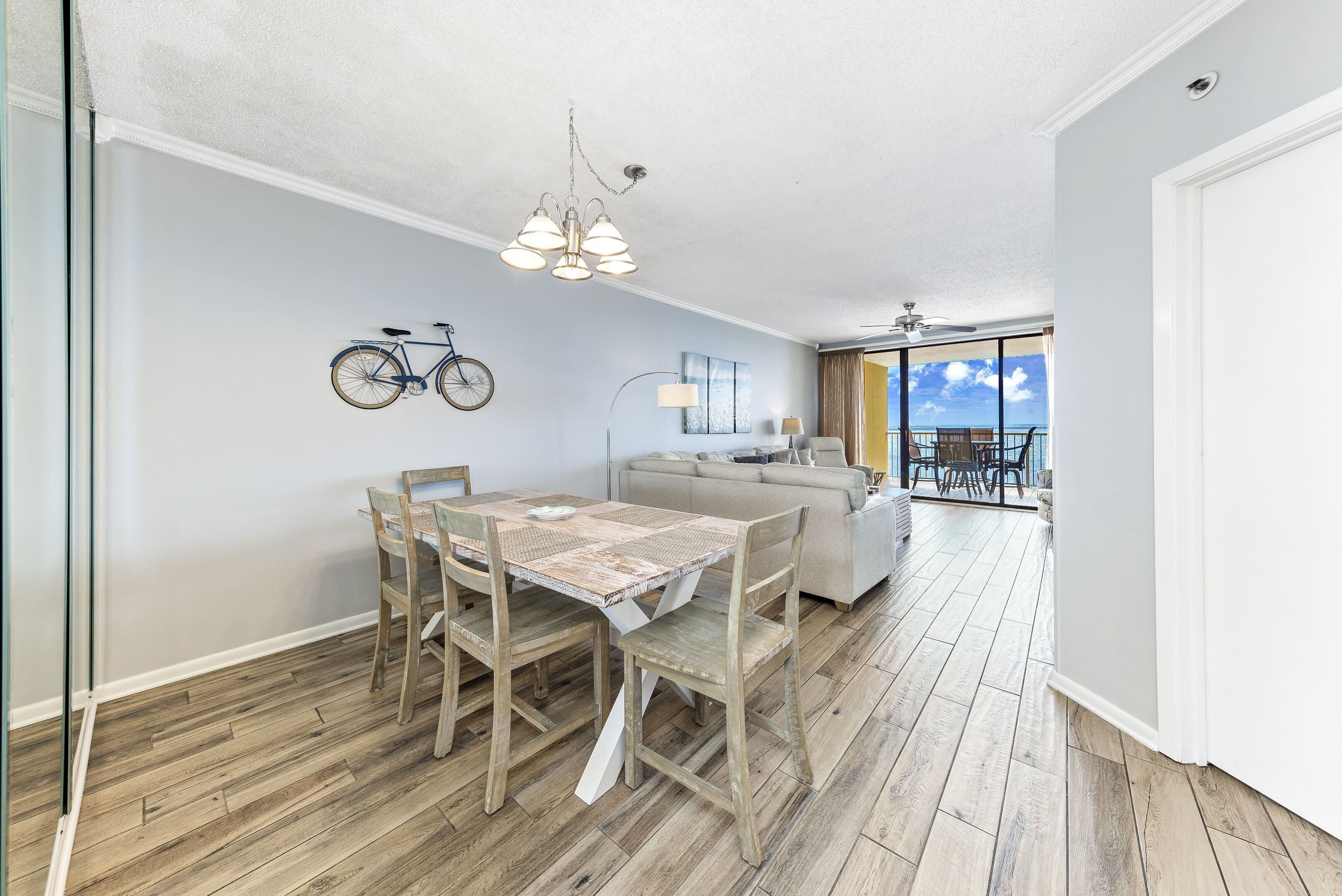 A dining area with a wooden table and chairs, a ceiling fan, and a bicycle on the wall.