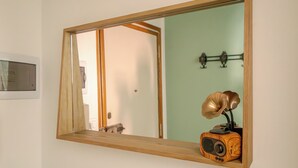 A mirror with a wooden frame reflecting a room with a green wall, a door, and a vintage radio on a shelf. - Italianway - Costaguta 75 (Rapallo)
