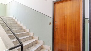 A staircase with marble steps and a wooden door with a metal handle. - Italianway - Costaguta 75 (Rapallo)