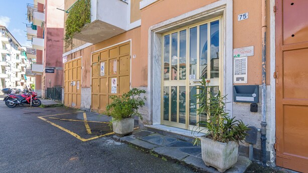 A building with numbered doors, a motorcycle parked outside, and potted plants in front. - Italianway - Costaguta 75 (Rapallo)