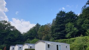 A row of mobile homes with picnic tables in a grassy area, surrounded by dense forest. - Chalet in Olloy-sur-viroin With Patio (Viroinval)