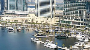 A marina with multiple yachts docked, surrounded by modern high-rise buildings. - 1612 Damac Reva Residences (Dubai)