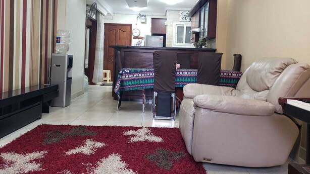 A living room with a beige sofa, a red and white rug, a dining area with a table and chairs, and a water dispenser. - Cozy 2-bedroom apartment with WiFi, AC in awesome Giza Governorate (Giza Governorate)