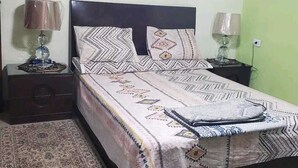 A bedroom with a bed, nightstands, lamps, a patterned rug, and wall art. - Cozy 2-bedroom apartment with WiFi, AC in awesome Giza Governorate (Giza Governorate)