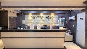 A hotel reception desk with a brick wall backdrop, a digital check-in kiosk, and a reception counter.
