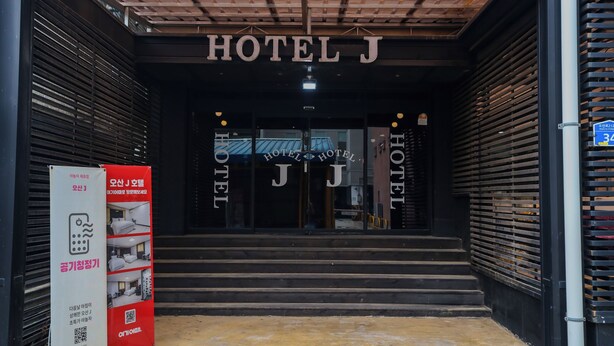 Der Eingang zum HOTEL J mit modernem Design, gekennzeichnet durch eine auffällige Beschilderung und eine Treppe zum Eingang.