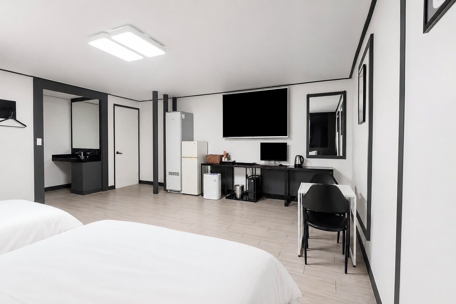 Une chambre d’hôtel avec deux lits, un bureau avec un ordinateur, un réfrigérateur, une poubelle et un miroir.