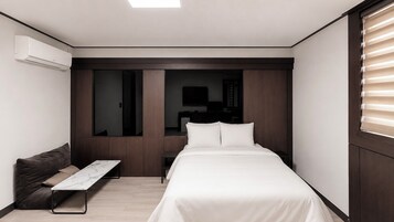 Una habitación de hotel moderna con cama, sofá, una mesita y armario empotrado.