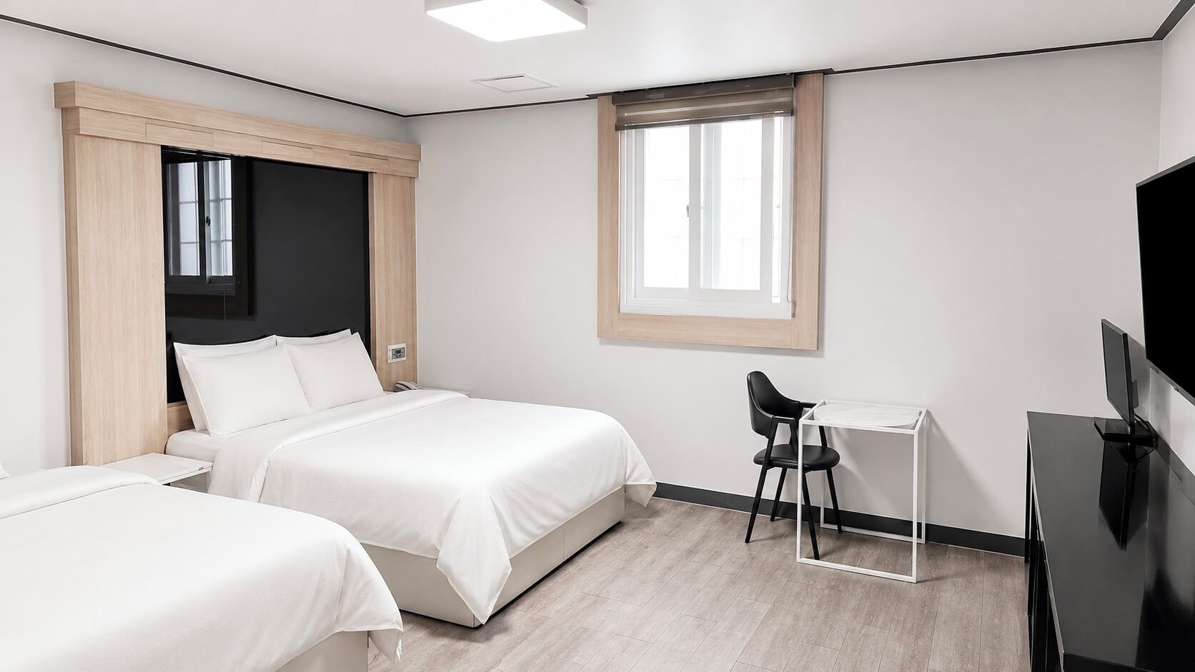 Habitación de hotel con dos camas, un escritorio, una silla, un televisor y una ventana.