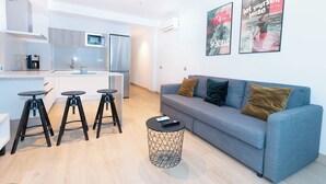 Ein modernes Wohnzimmer mit einem grauen Sofa, drei schwarzen Hocker und einem runden Couchtisch.