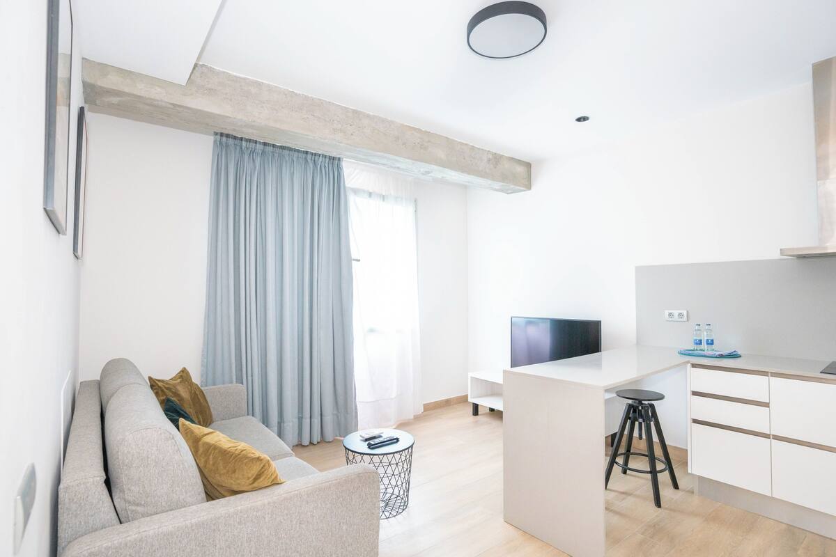 Um apartamento moderno com sala de estar, cozinha compacta e área de jantar.