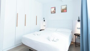 Ein modernes Schlafzimmer mit einem großen Bett, weißen Wänden und einer Deckenleuchte.