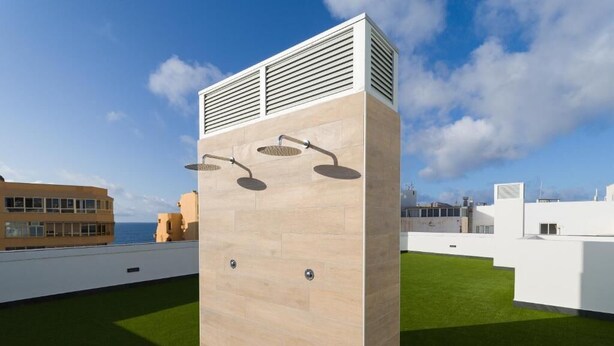 Eine moderne Dachterrasse mit minimalistischem Design, mit einer hellen Wand, einer integrierten Klimaanlage und zwei Wandbrausen.