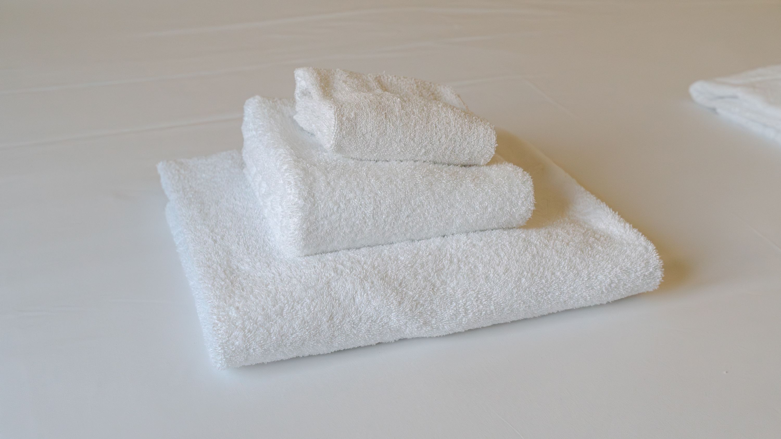A stack of white towels on a white surface.