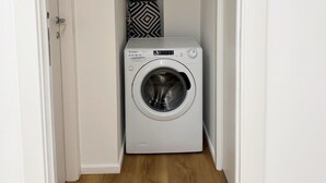 Une buanderie équipée d’un lave-linge et d’un sèche-linge à chargement frontal, d’un panier à linge à motifs et d’un plancher en bois.