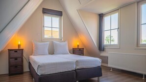 A bedroom with a bed, two bedside tables, a window, and a radiator. - Charming Sauna Home Near Alkmaar (West-Graftdijk)