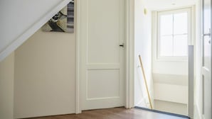 A hallway with a white door, wooden flooring, and a window with blinds. - Charming Sauna Home Near Alkmaar (West-Graftdijk)