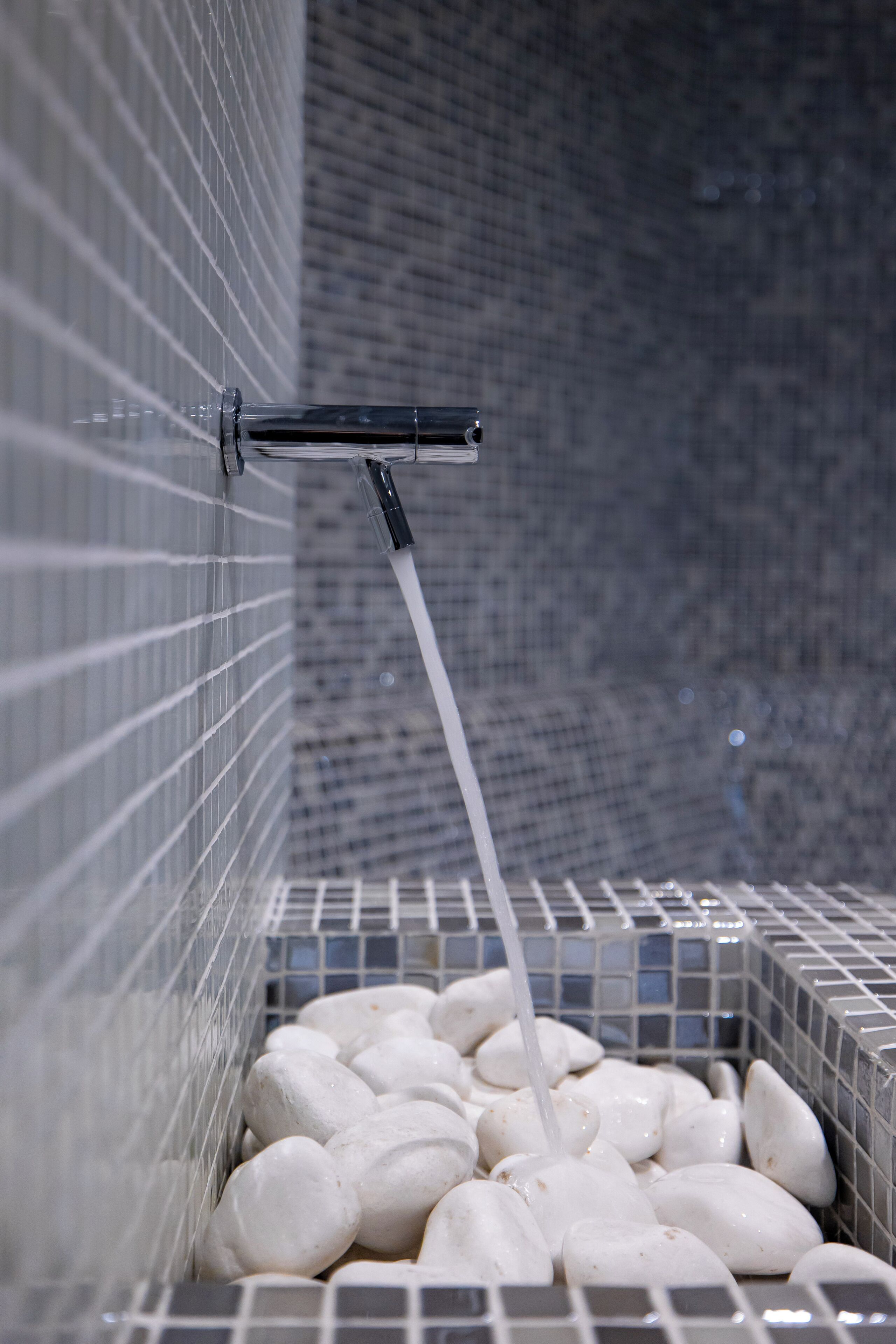 A tiled wall with a water feature.