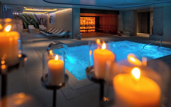 A spa area with a hot tub, candles, and lounge chairs.