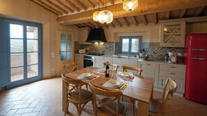 Una cocina amplia con vigas de madera, una mesa de comedor preparada para cuatro personas y un refrigerador rojo.