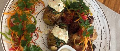 Un plato de comida con diferentes verduras y un recipiente pequeño con salsa.