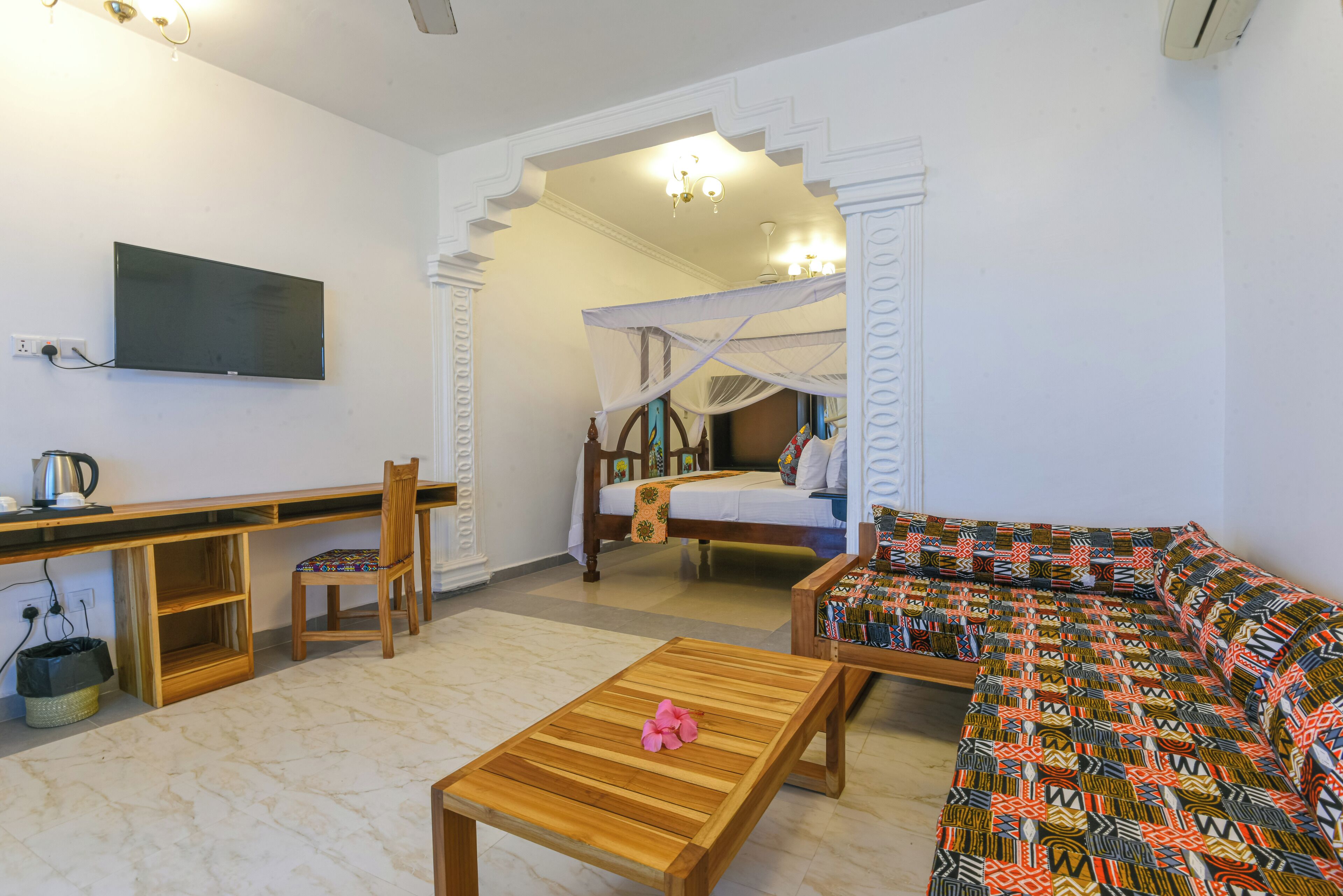 Una habitación con una cama, un sofá, un escritorio y un televisor.