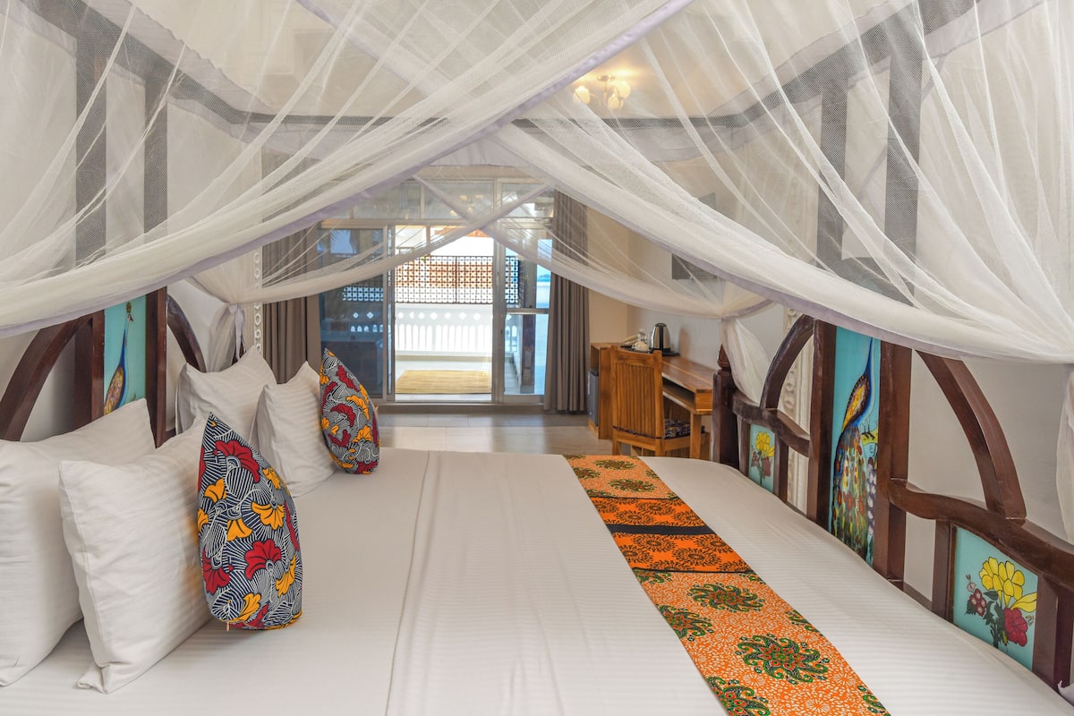 Una habitación con cama, escritorio y vistas al exterior.
