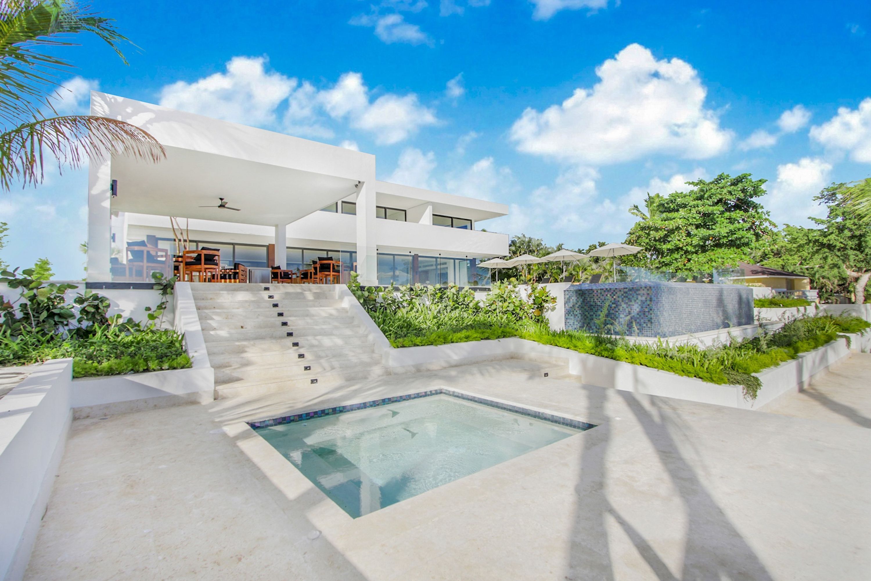 A modern house with a swimming pool, outdoor seating, and a staircase leading to the entrance.