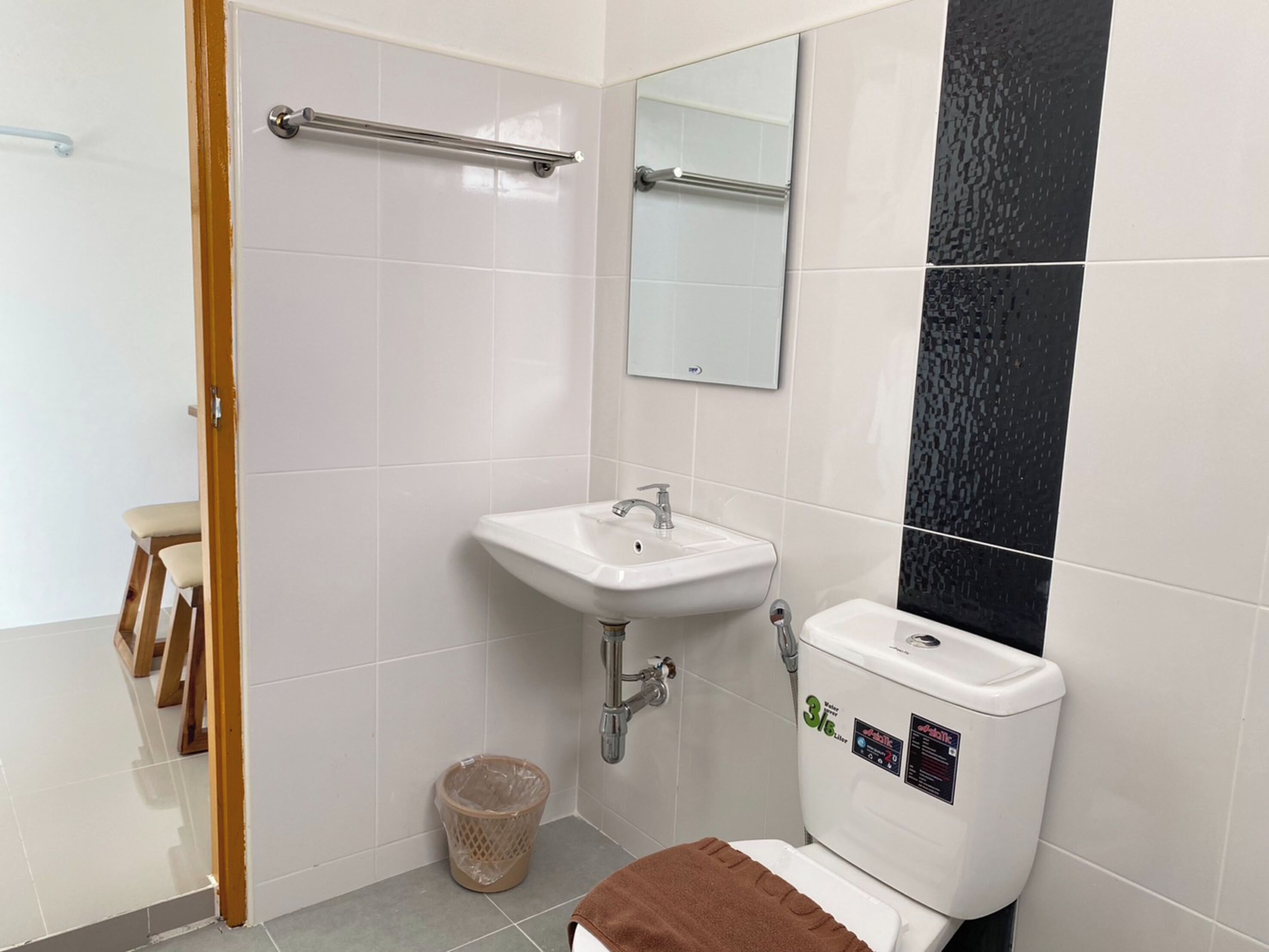 Un baño con lavamanos blanco, inodoro, espejo y cubo de basura.