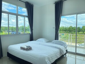 A bedroom with a bed, two windows, and a view of greenery and a pool. - Dino Homestay (Mae Taeng)
