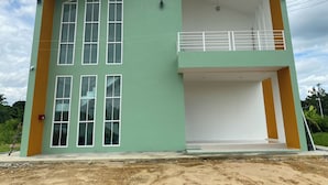 A two-story building with a flat roof, large windows on the ground floor, and a balcony on the upper floor. - Dino Homestay (Mae Taeng)