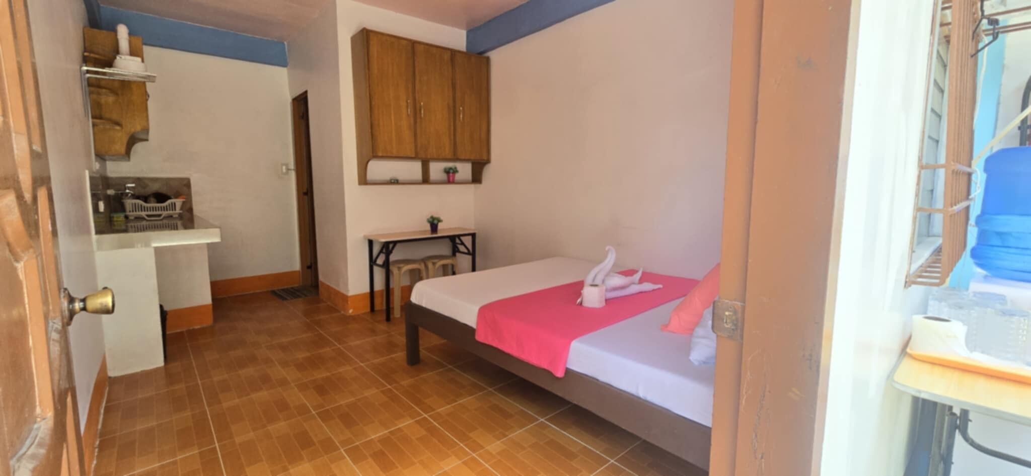 A small room with a bed, a desk, and a cabinet.