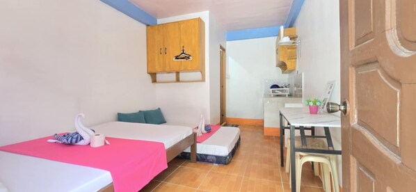 A room with two beds, a small kitchenette, and a wooden cabinet with a hanger. - Bebs and Jocel Apartment (Panglao)