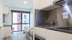 Una cocina moderna con una campana de acero inoxidable, un lavamanos integrado y una ventana con vistas a edificios.