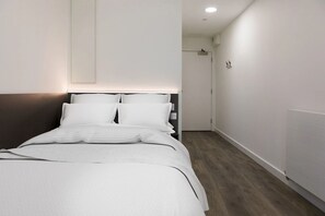 A modern bedroom with a bed, bedside tables, and a nightstand. - For Students Only Chic Studios and Ensuites at Chapter Highbury II in London (London)