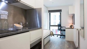 Una cocina moderna con un ventanal grande, una silla de oficina negra y una pequeña zona de escritorio.