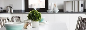 Una cucina moderna con mobili bianchi, elettrodomestici in acciaio inossidabile e una piccola pianta in vaso sul piano di lavoro.