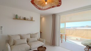 Un salon comprenant un canapé, deux tables d’appoint, un ventilateur de plafond et une vue sur l’extérieur.