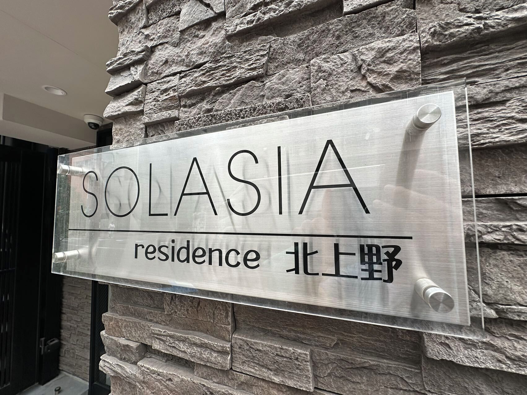 A sign for Solasia residence with a stone wall background.